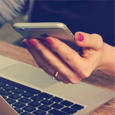 Mulher com as unhas pintadas de rosa segurando um celular